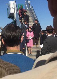 Натали в костюме розового цвета, шляпке и перчатках спускается с трапа самолета