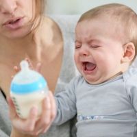 dziecko pochyla się i płacze podczas karmienia